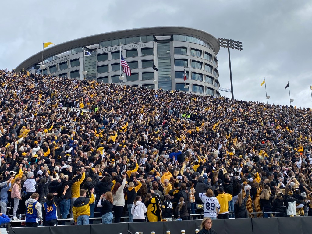 Thousands of fans in the stands turn away from the court and wave to children at the hospital behind Kinnick Stadium.