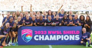 Members of the NWSL's San Diego Wave are pictured in team uniforms holding up a banner that reads "2023 NWSL Shield Champions"