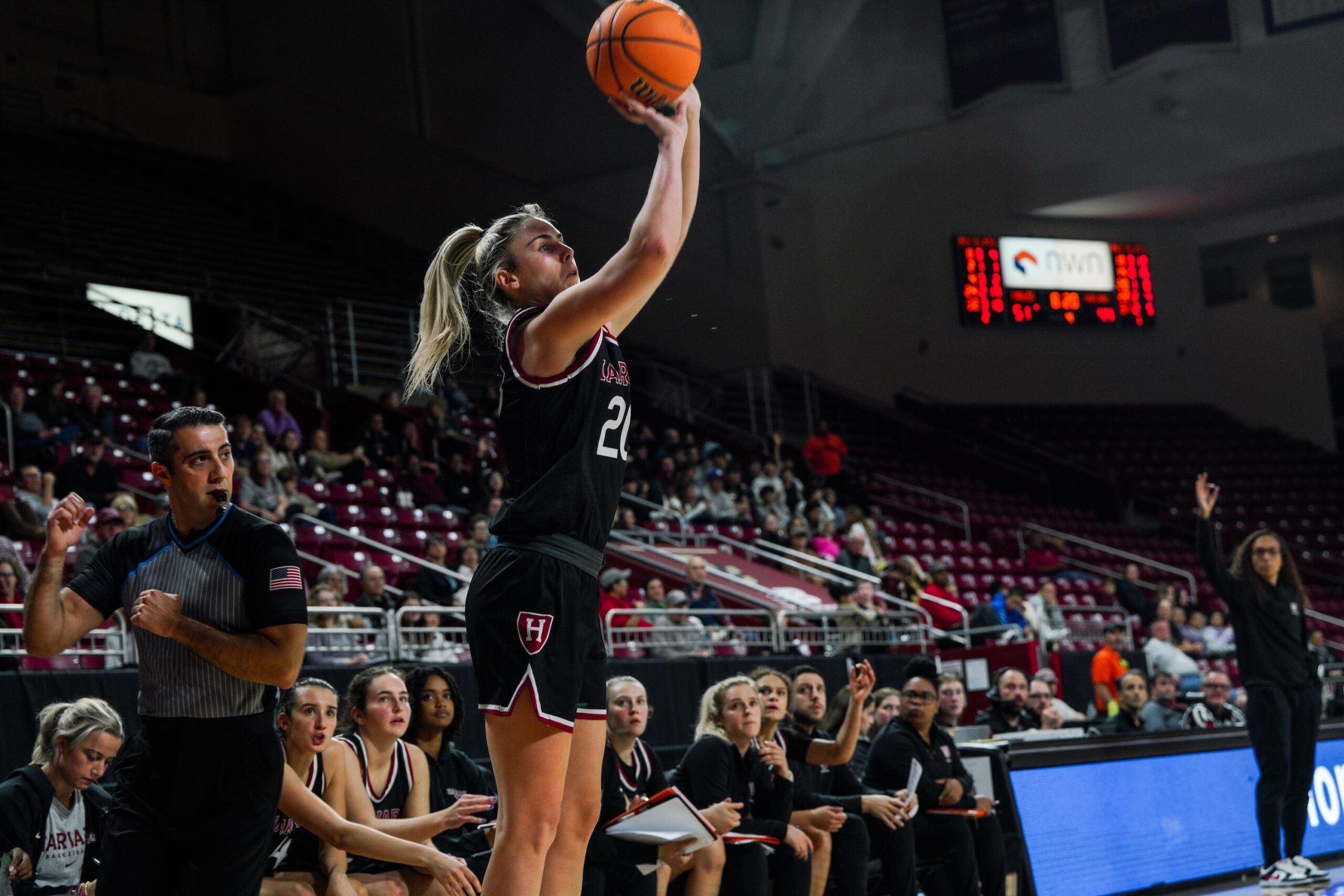 Harvard guard Lola Mullaney shoots an open right-handed jump shot in front of her team's bench.