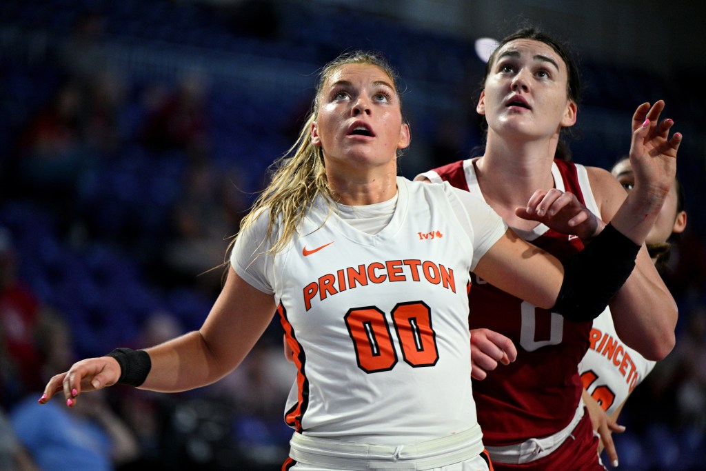 Princeton forward Ellie Mitchell stands in front of Oklahoma center Beatrice Culliton with her arms out. Both players look up, awaiting a rebound opportunity.
