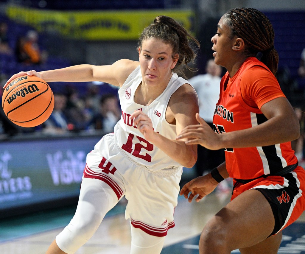Indiana guard Yarden Garzon dribbles the ball with her right hand and dips her left shoulder to shield the ball as Princeton guard Chet Nweke slides her feet to defend.