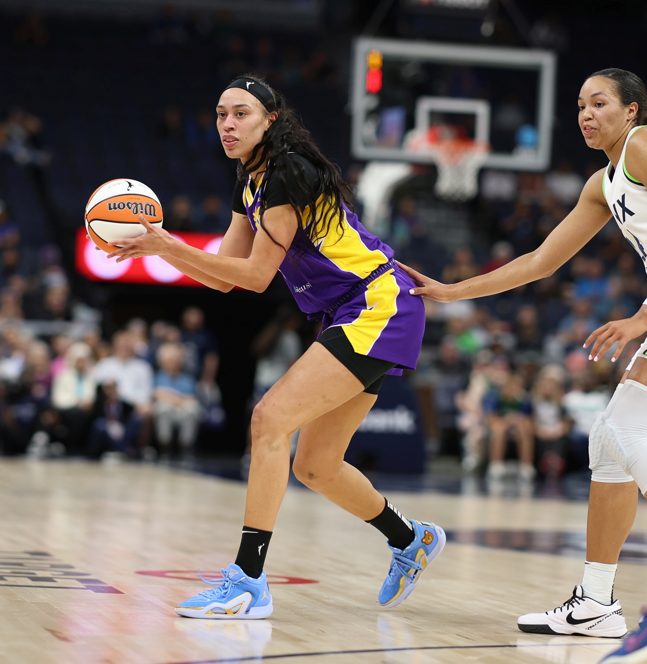 Dearica Hamby, wearing purple and yellow Sparks jersey, drives to the basket against Lynx forward Naphessa Collier, wearing white and blue.