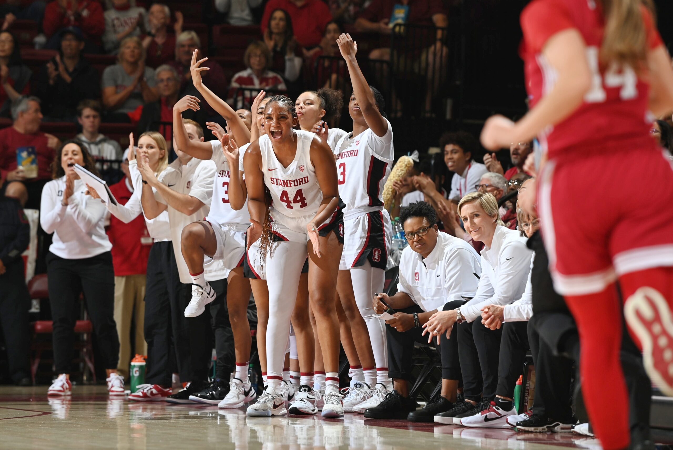 Pac-12 action: Kiki Iriafen (44) smiles and claps for her Stanford teammates from the bench, alongside fellow Stanford players and coaches.