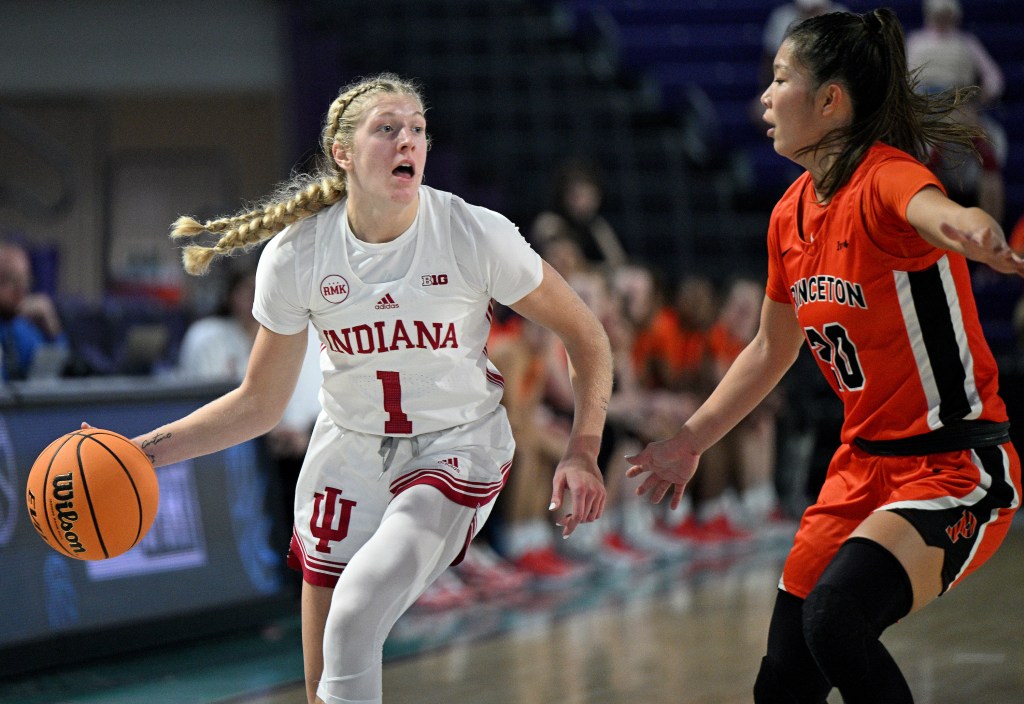 Indiana guard Lexus Bargesser looks up as she dribbles the ball with her right hand. Princeton guard Kaitlyn Chen slides laterally to defend her.