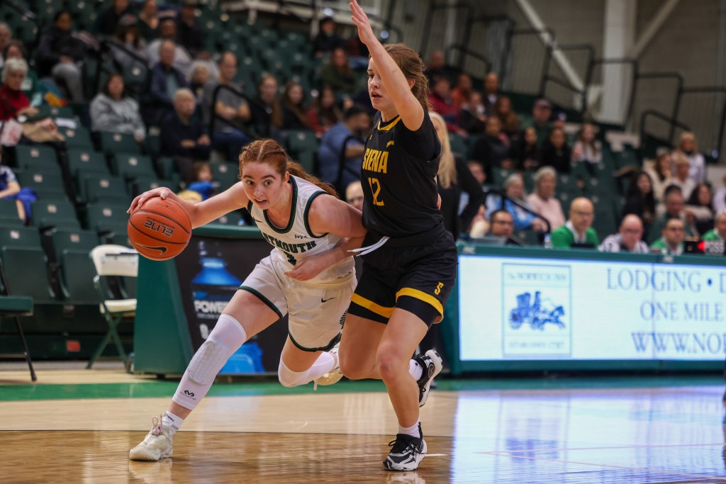 Dartmouth point guard Nina Minicozzi dribbles with her right hand, her torso leaning forward and down to help shield the ball from a defender on her hip.