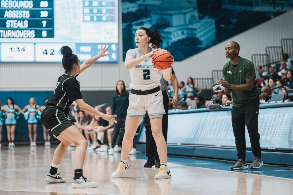 Columbia guard Ava Sciolla has her eyes up as she holds the ball on the left side of her body. A Wagner player is in front of her in a defensive stance.