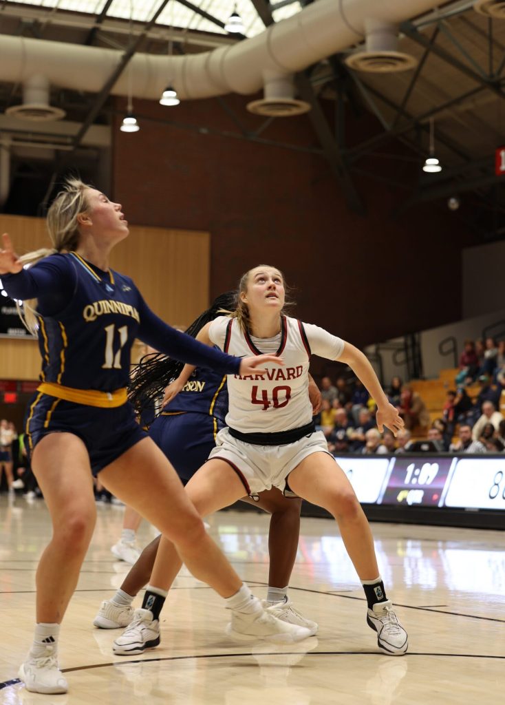 Harvard freshman Abigail Wright bends her knees and reaches her arms back to box out a Quinnipiac player. She looks up to track the path of the ball.
