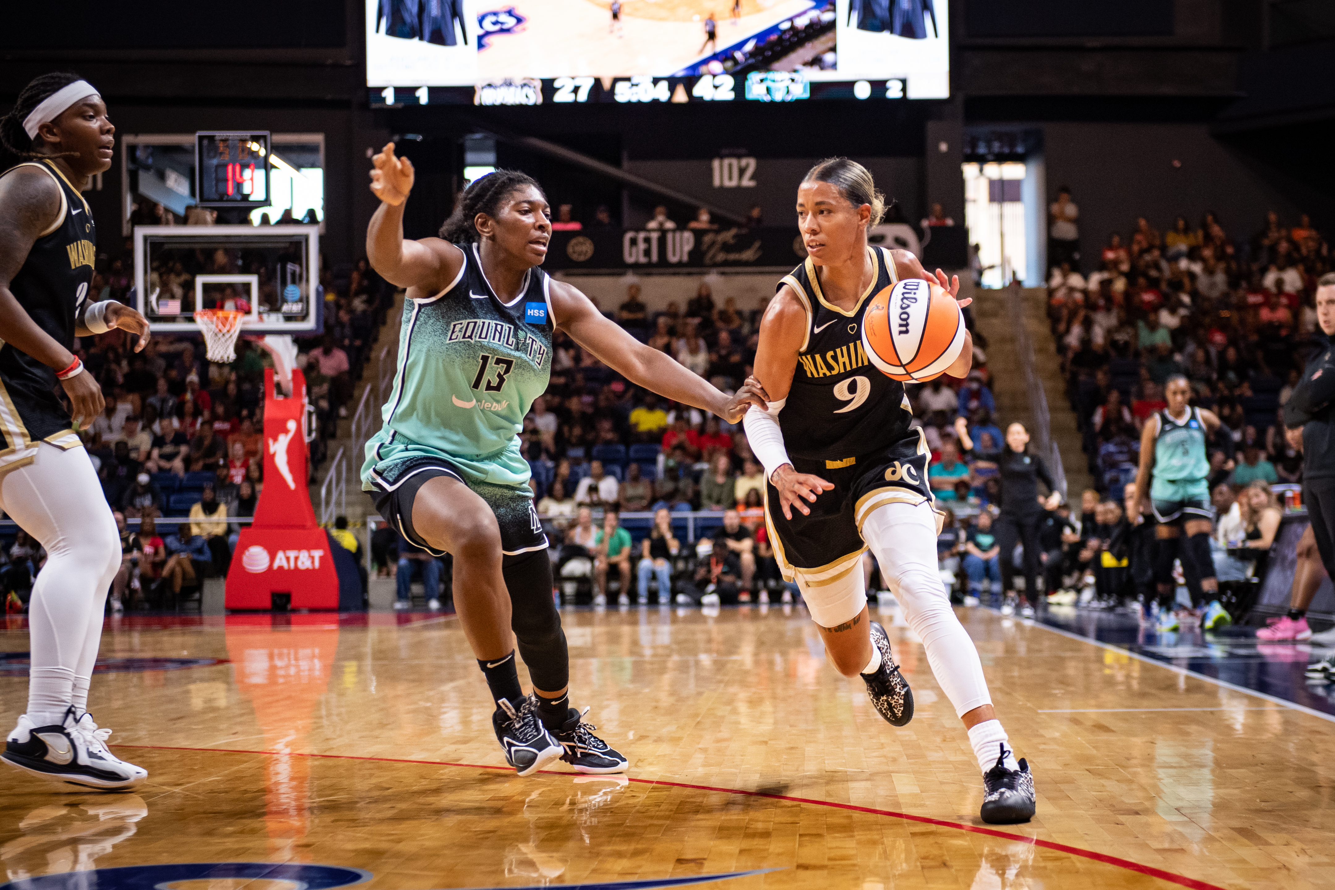 Liberty forward Jocelyn Willoughby, wearing the Liberty seafoam and black uniform, guards Mystic guard Natasha Cloud, wearing Washington's black and gold jersey.