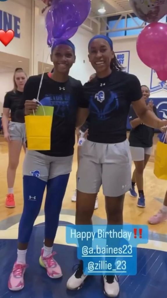 Azan Baines and Brazil Harvey Carr stand on a basketball court arm in arm holding birthday balloons and gifts