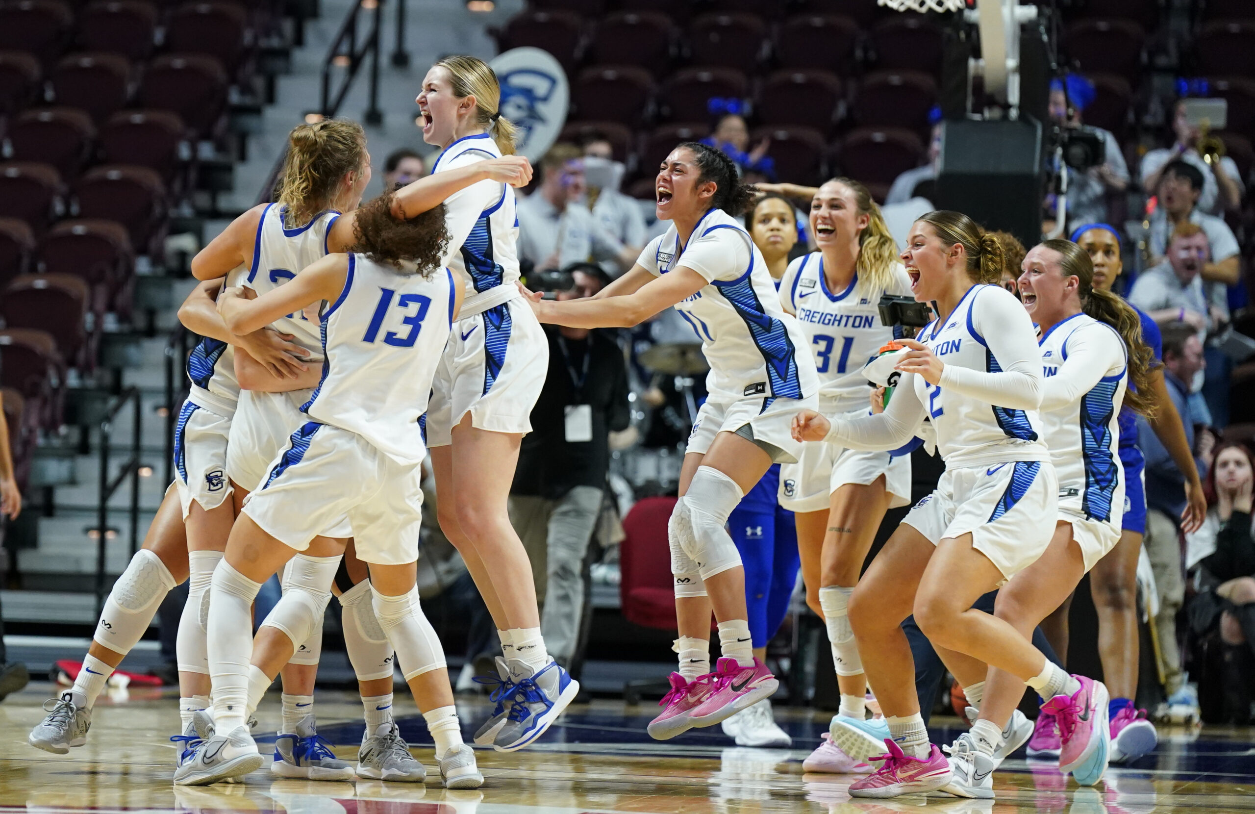 Creighton Bluejays guard Morgan Maly (30) celebrates with her teammates after making the winning basket in the BIG EAST Tournament. The team is wearing white and blue home jerseys.