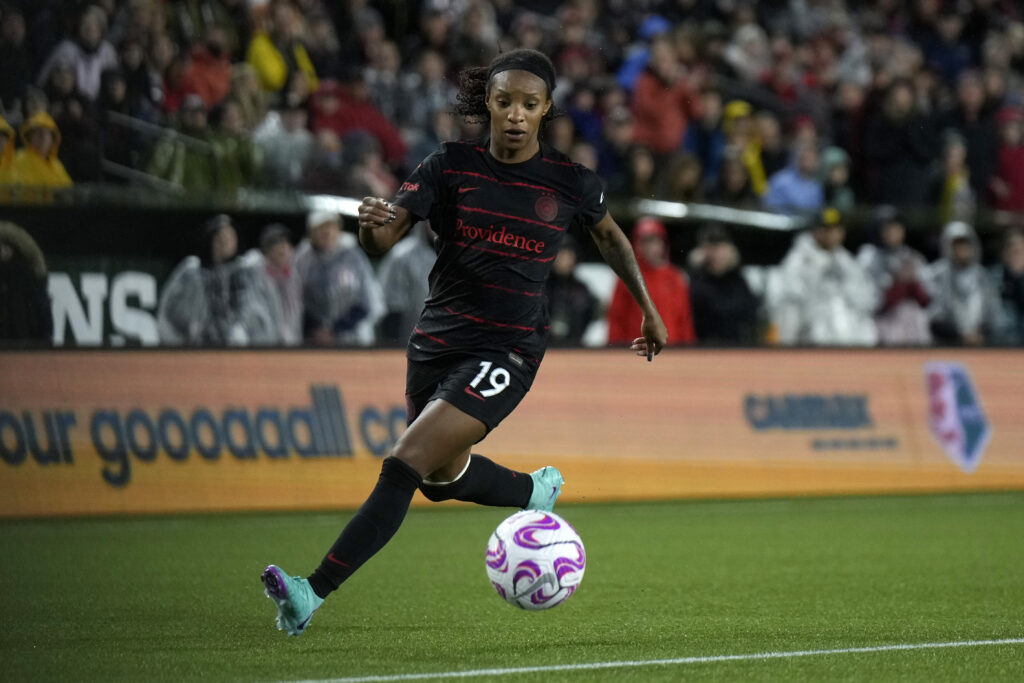 Crystal Dunn, wearing a black Portland FC jersey with the number 19 on the left side of her shorts, takes the ball up the field.