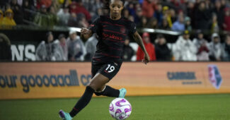Crystal Dunn, wearing a black Portland FC jersey with the number 19 on the left side of her shorts, takes the ball up the field.
