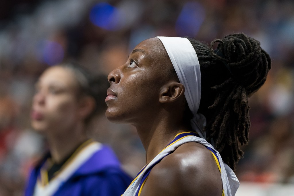 Nneka Ogwumike stands in profile view with her hair in a bun and a white headband as she looks up into the distance.