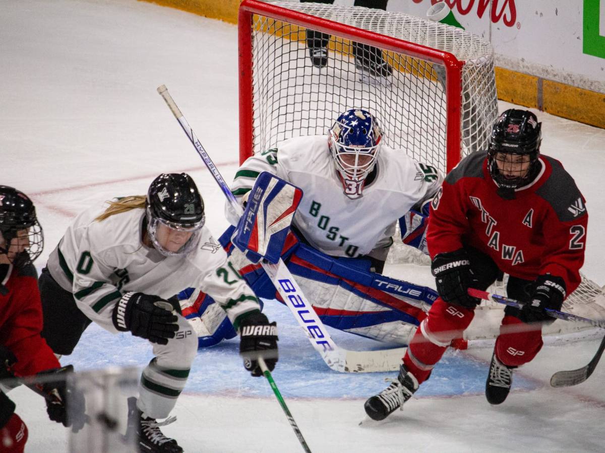 Emily Clark chases a puck in front of Aerin Frankel in the Boston net.