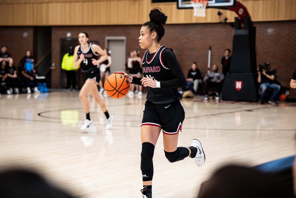 Harvard guard Harmoni Turner dribbles the ball with her right hand near midcourt, with no defender on her.