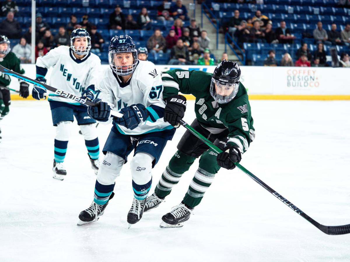 Megan Keller, wearing a green home uniform, and Emma Woods, wearing a white away uniform, battle for positioning.