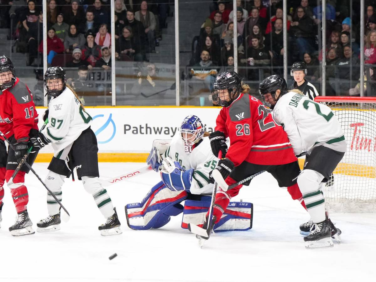 Boston players, wearing white, battle defensively with Ottawa, wearing red, in front of Aerin Frankel.