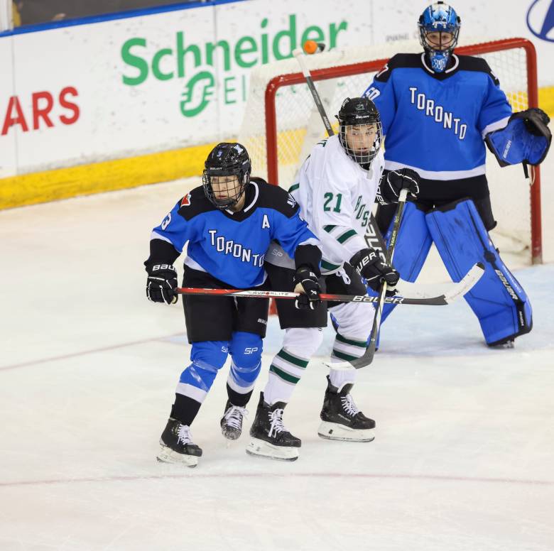 Hilary Knight, wearing a white away uniform, and Jocelyne Larocque, wearing a blue home uniform, battle for positioning.