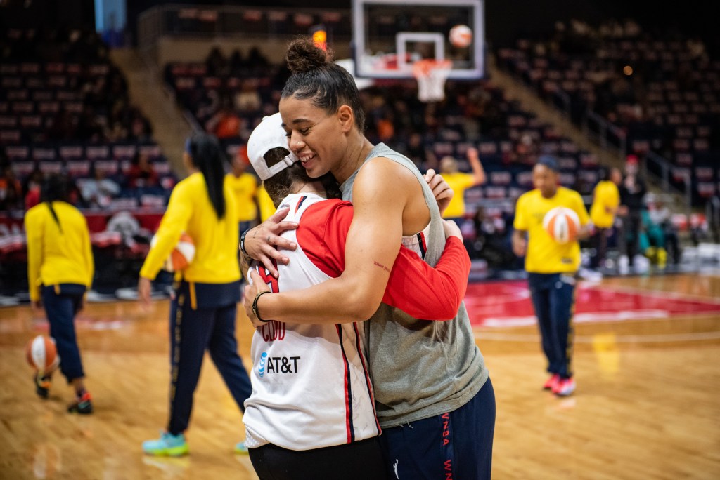 Washington Mystics guard Natasha Cloud closes her eyes as she hugs a fan who is wearing her jersey.