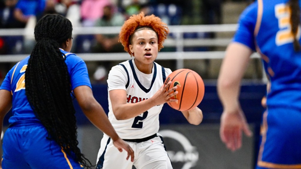 Iyanna Warren holds the basketball as two defenders look on