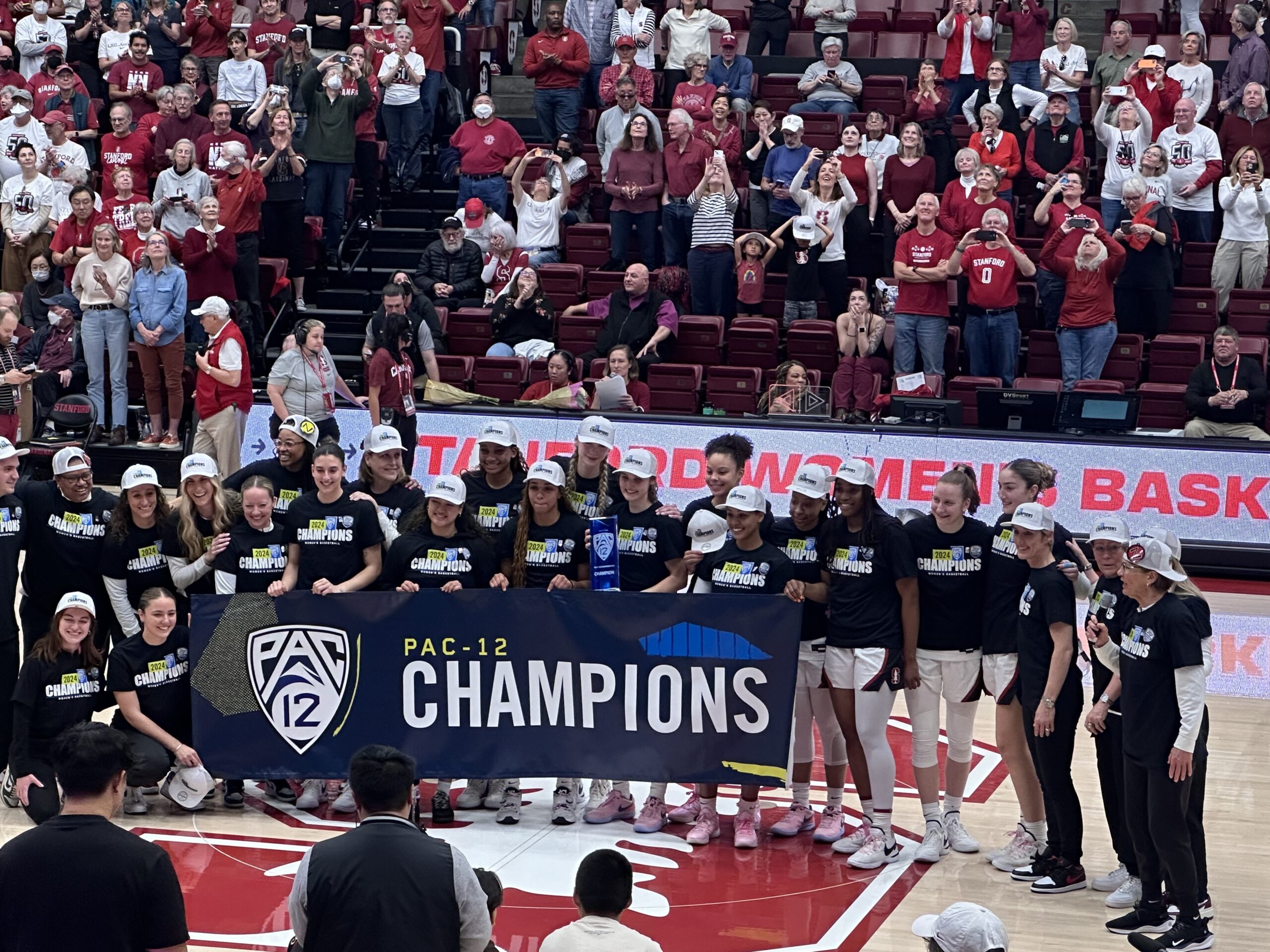 Stanford gathers at half court with their Pac-12 Championship banner and t-shirts.