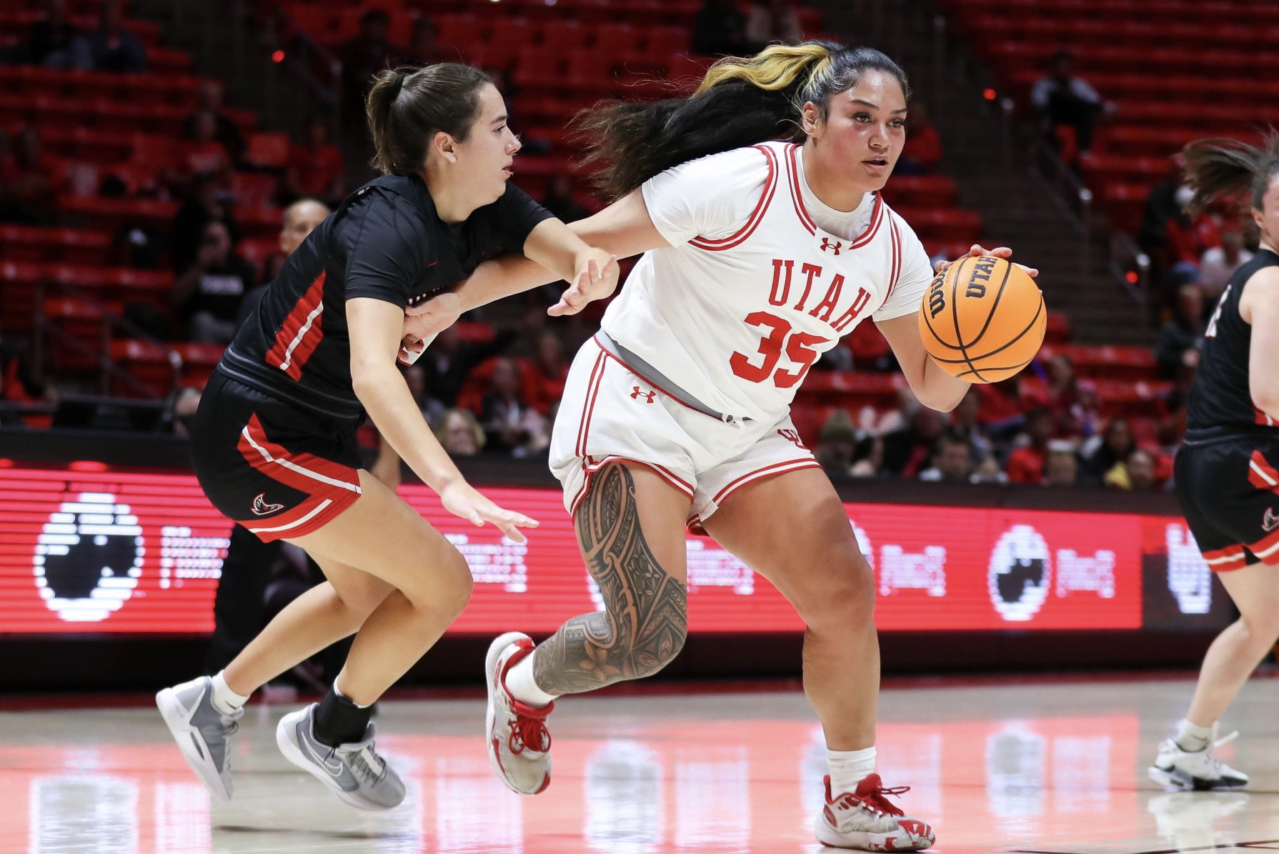 Utah's Alissa Pili dribbles the ball with her left hand and uses her right arm to try to fend off a defender.