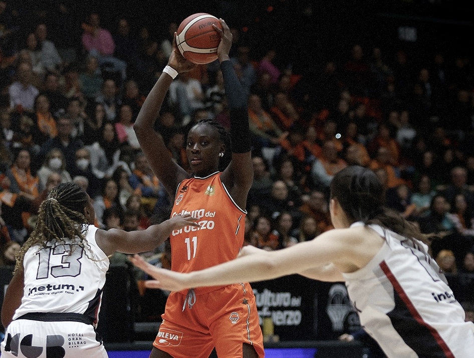 18-year-old Spanish center Awa Fam of Valencia pictured holding the ball above her head surveying the court.