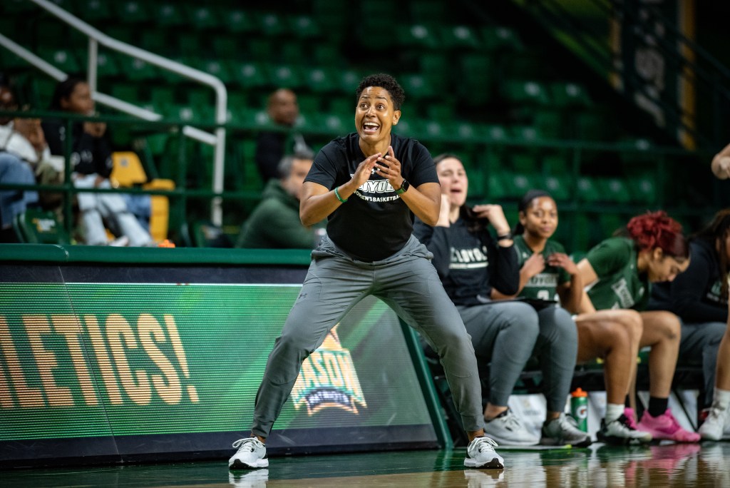 Loyola head coach Banielle O’Banion smiles and claps on the sideline