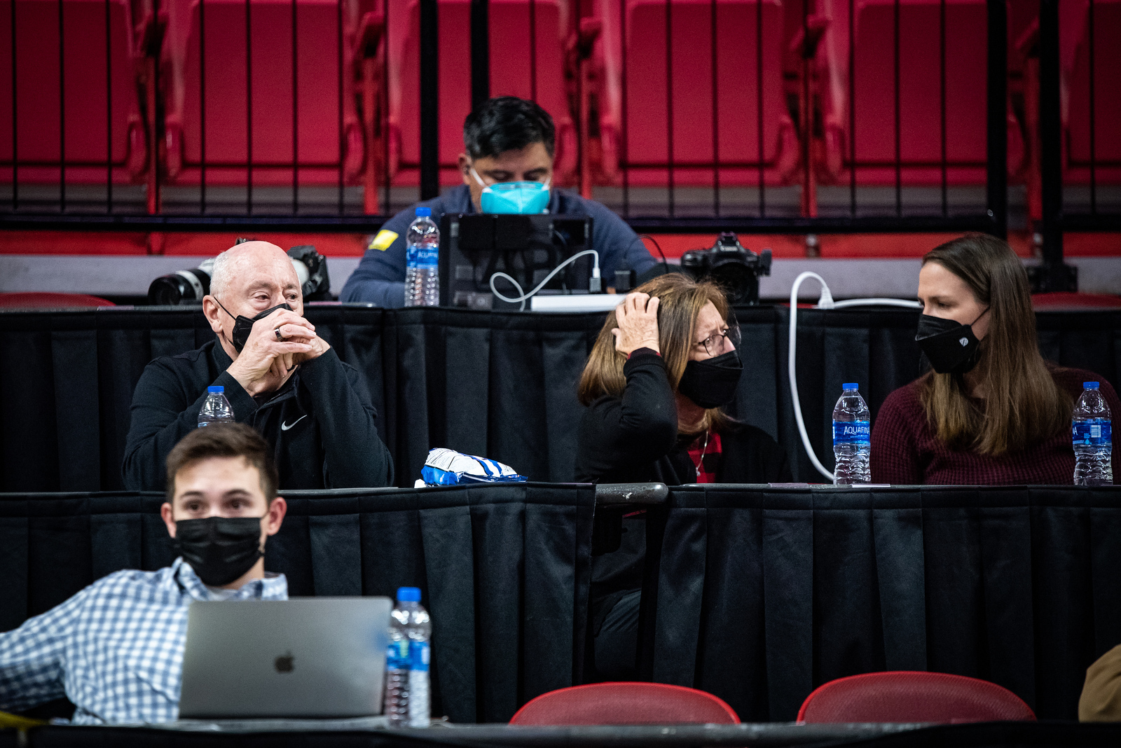 Washington Mystics general manager Mike Thibault sits on press row, next to two women who are having a conversation.