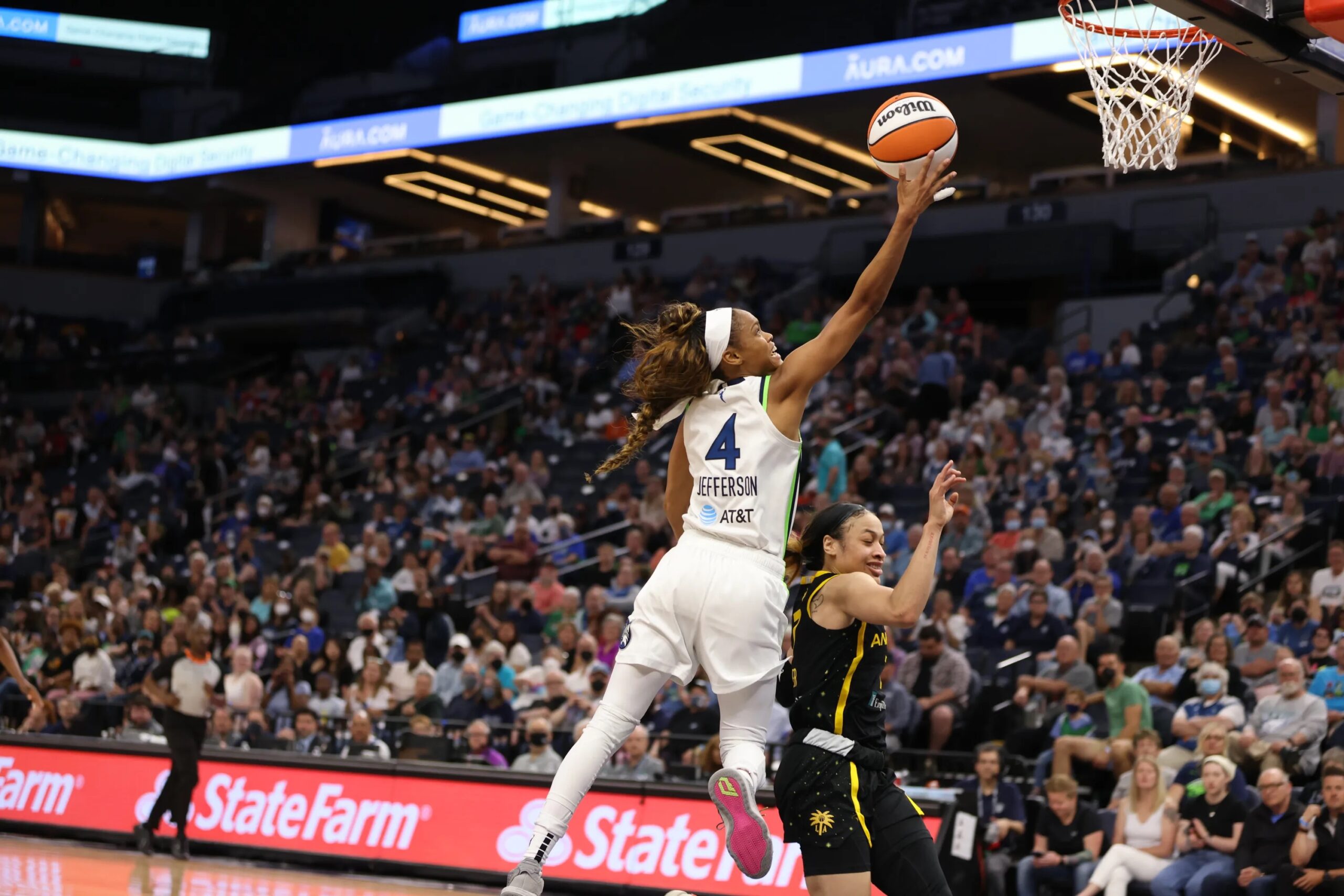 Minnesota Lynx point guard Moriah Jefferson goes up with the ball in one hand as she attempts a layup over a ducking Los Angeles Sparks point guard Chennedy Carter.