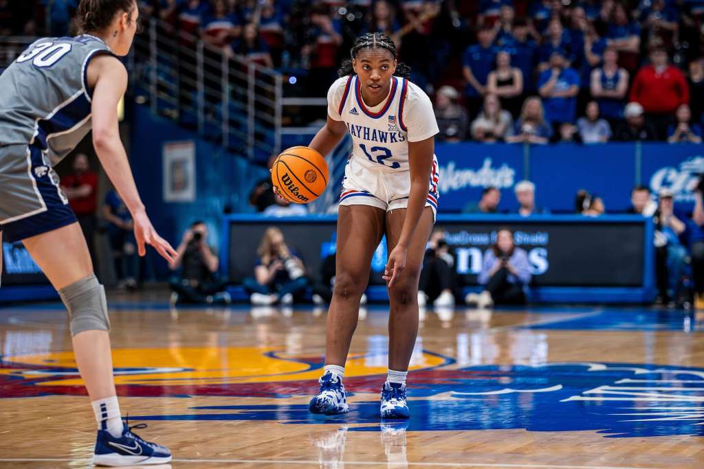 Kansas junior guard S'Mya Nichols dribbles the basketball with her right hand over the Kansas logo at Allen Fieldhouse.