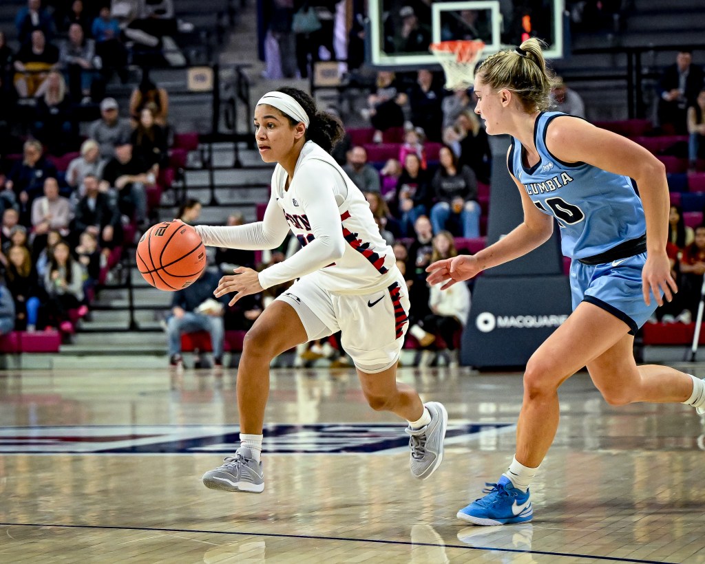 Penn guard Mataya Gayle dribbles the ball with her right hand as Columbia guard Kitty Henderson runs alongside her.