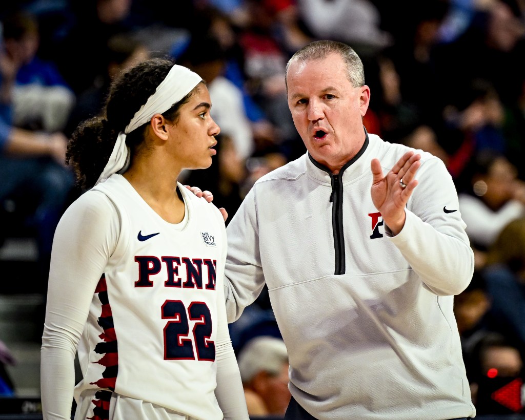 Penn head coach Mike McLaughlin gestures with his left hand and has his right hand on freshman point guard Mataya Gayle's shoulder as he gives her instructions during a game.