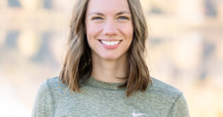 Former gymnast Gabi Rooker will compete in the US Marathon trials. Rooker is pictured in a gray Nike top against a green background.