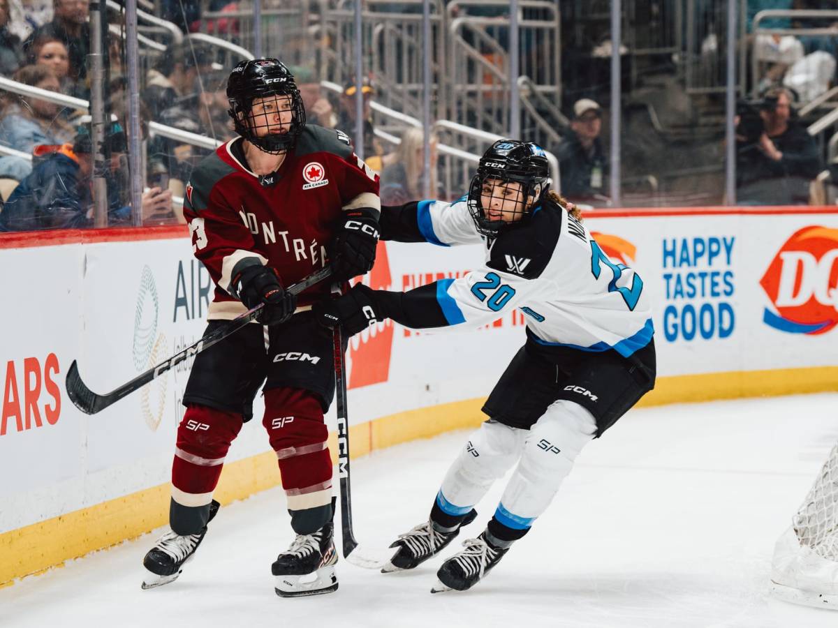 Nurse shoves Ambrose behind the net. Ambrose is upright wearing maroon, Nurse is more hunched over wearing white