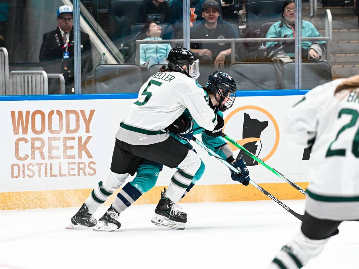 Keller defends a NY player. Keller's body is wrapped around her and she is wearing white, while the NY player is in teal.