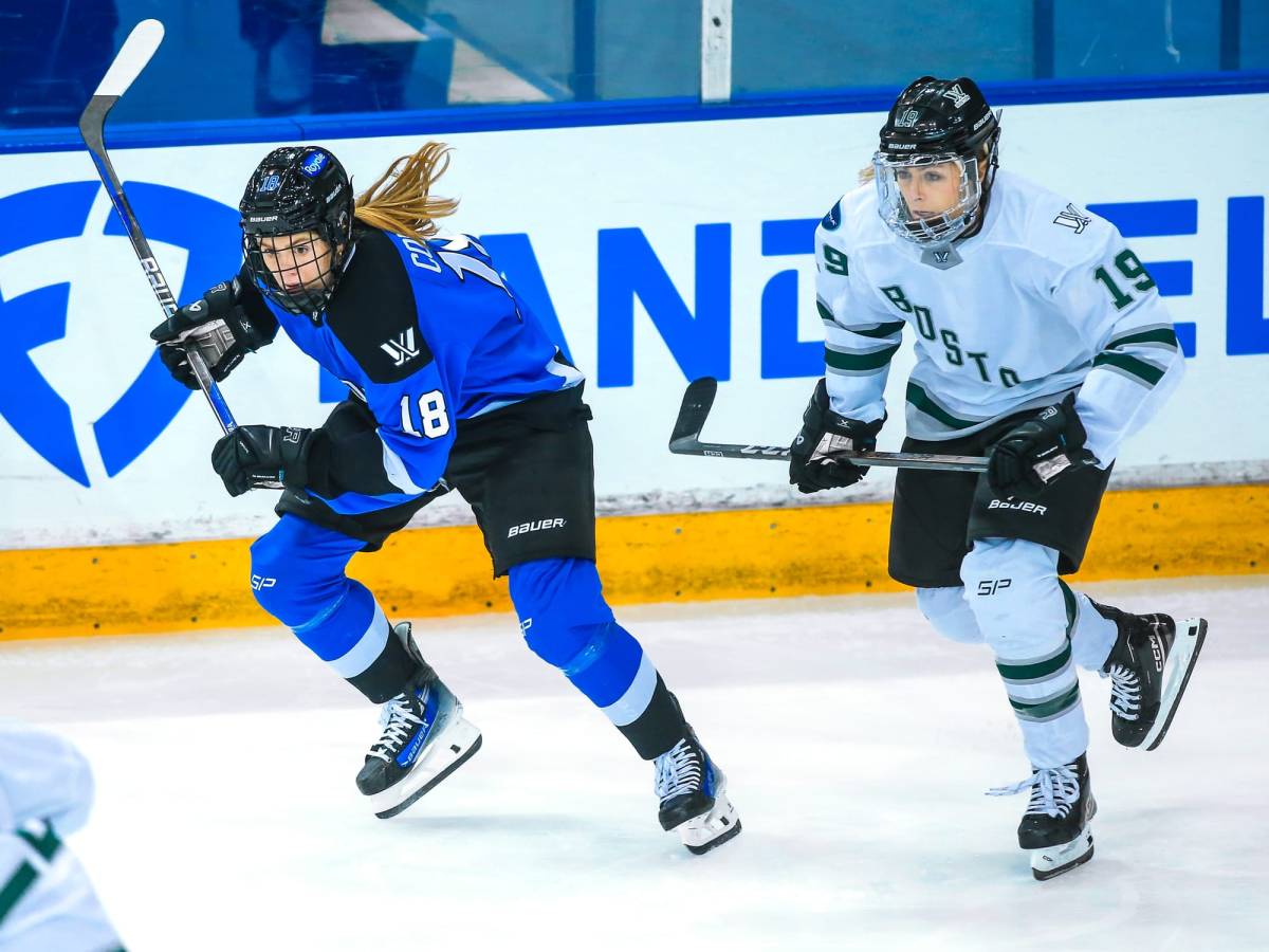 Gigi Marvin and Jesse Compher hunt the puck. Both are skating, with Compher (in blue) ahead of Marvin (in white).