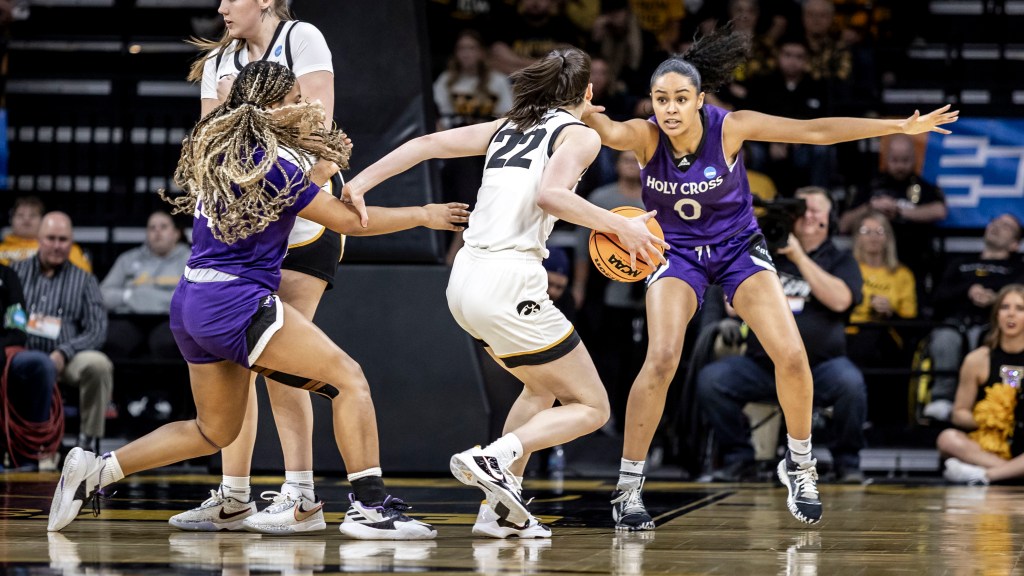 Holy Cross forward Callie Wright  puts pressure on Iowa guard Caitlin Clark