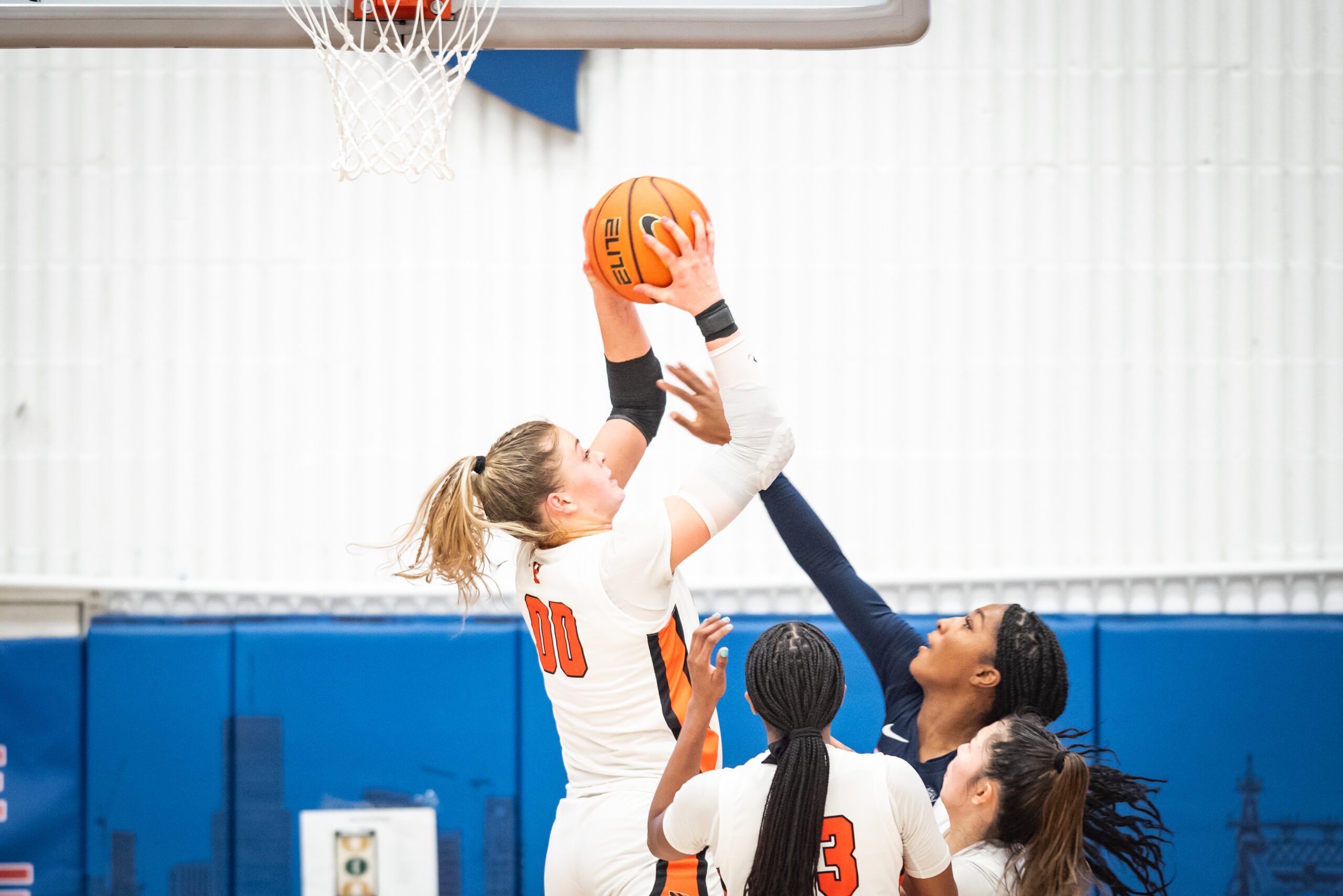 Princeton forward Ellie Mitchell grabs a rebound with two hands as a Penn player attempts to tip it away from her.
