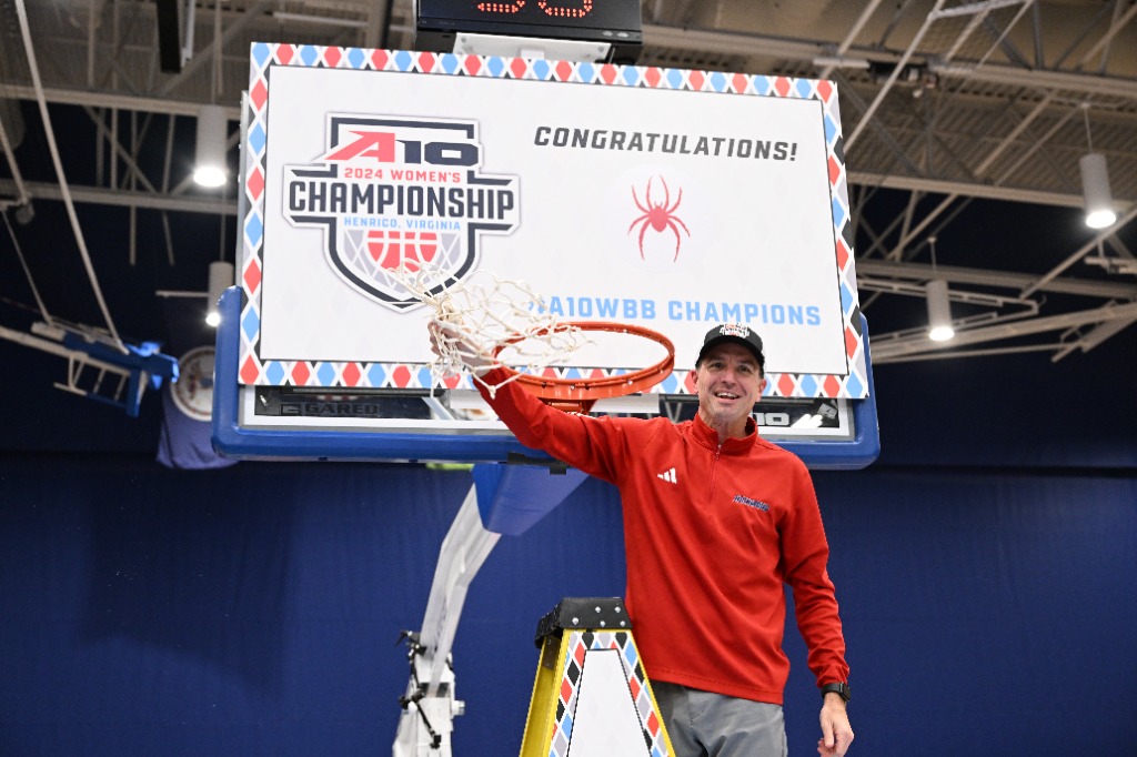 Richmond head coach Aaron Roussell waves the championship net around at the top of the ladder after cutting it down.