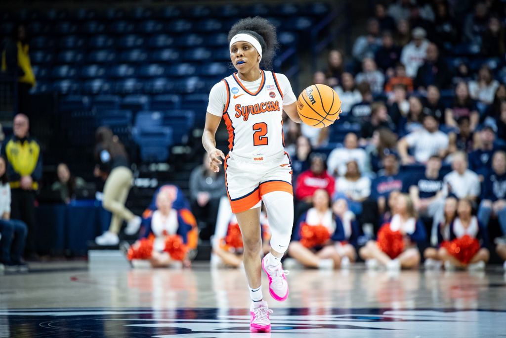Dyaisha Fair has the ball in her left palm as the dribbles the ball up the court, with her weight on her right foot and her left foot mid-step in the air.