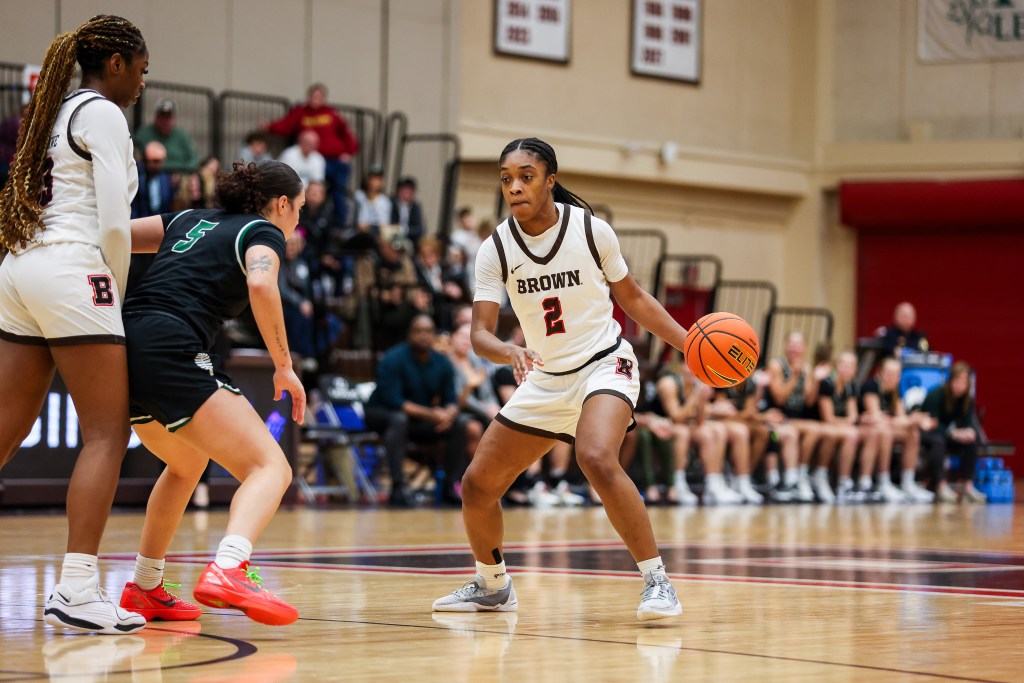 Brown guard Kyla Jones dribbles the ball with her left hand from near the top of the key. A teammate sets a backscreen on Jones' defender.