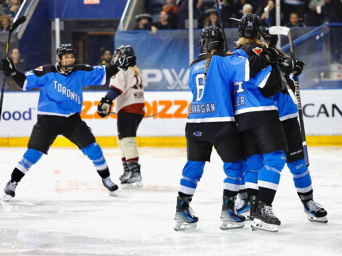Toronto players celebrate a goal against Montréal. They are in a group hug and wearing blue home jerseys.