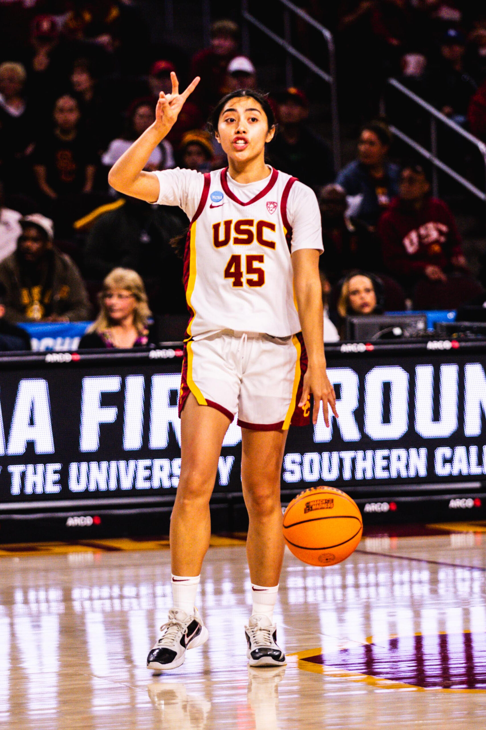 USC guard Kayla Padilla dribbles the ball with her left hand and puts two fingers up with her right hand to direct the offense.