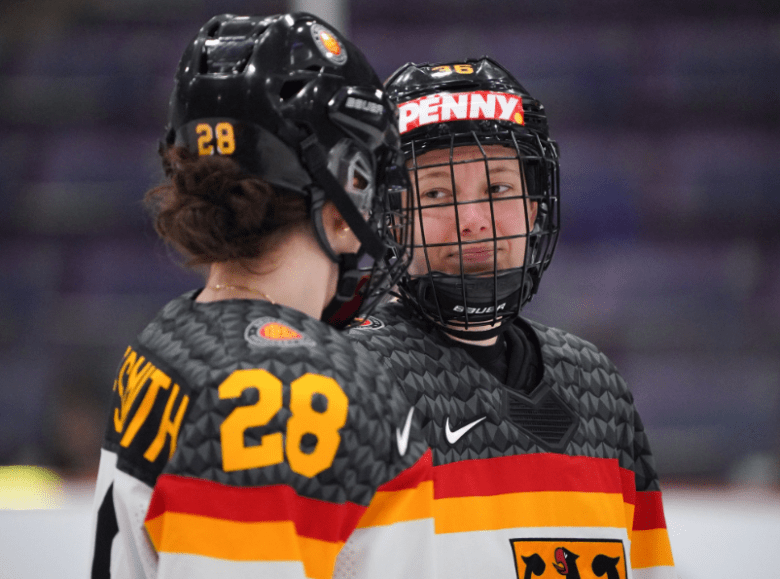Two German national team skaters looking at each other through caged helmets.