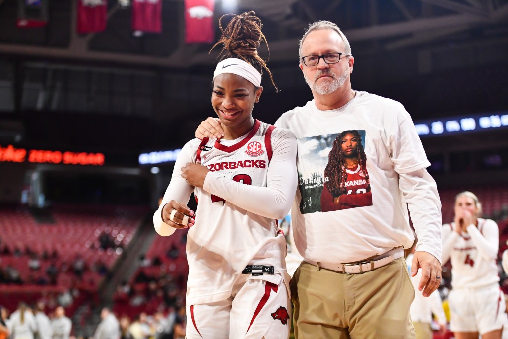 Wearing a T-shirt honoring fifth-year senior guard Makayla Daniels, Arkansas head coach Mike Neighbors puts his right hand on Daniels' shoulder as they walk off the court.