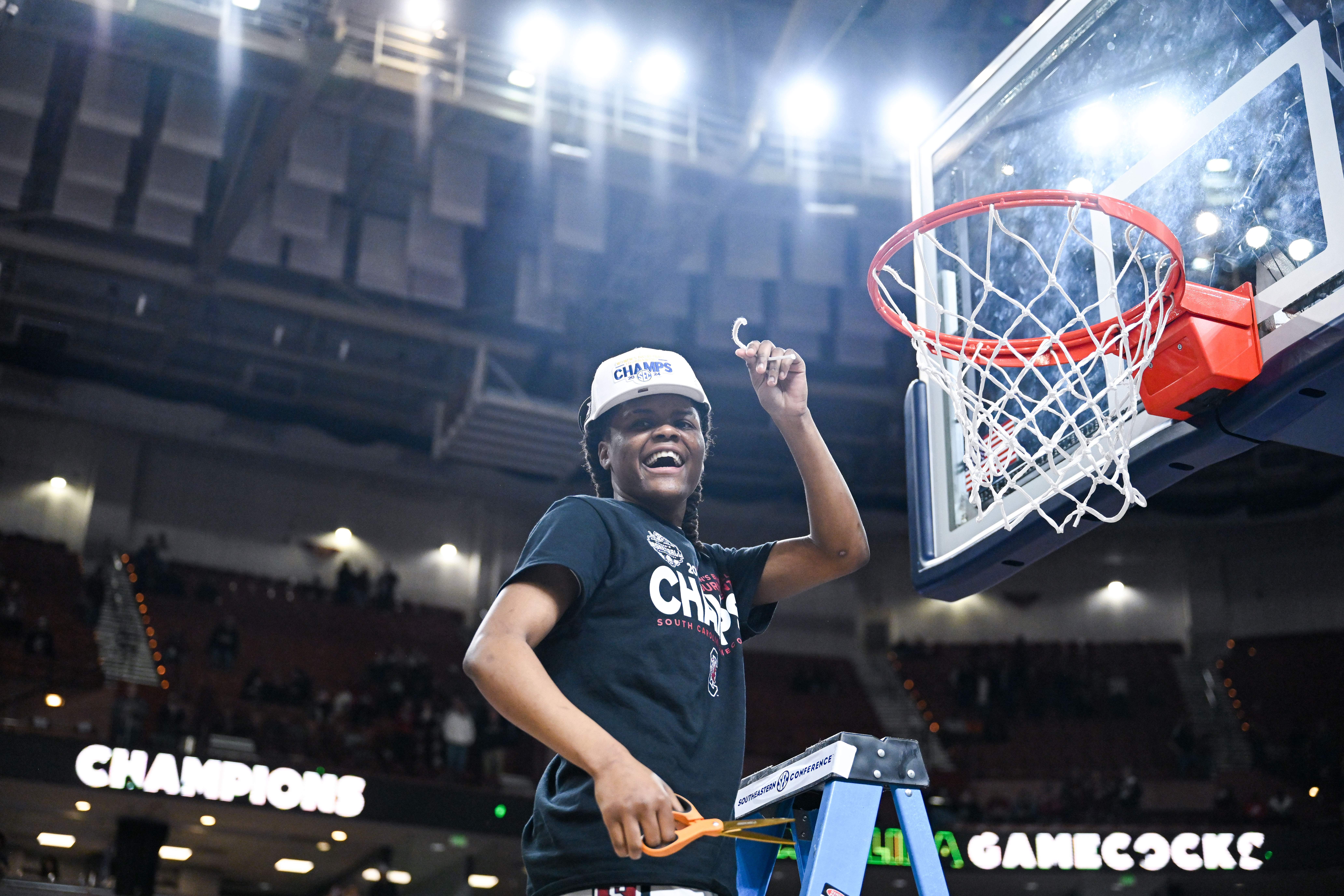 South Carolina's MiLaysia Fulwiley stands on a ladder and holds up her piece of the net after winning the 2024 SEC Tournament.