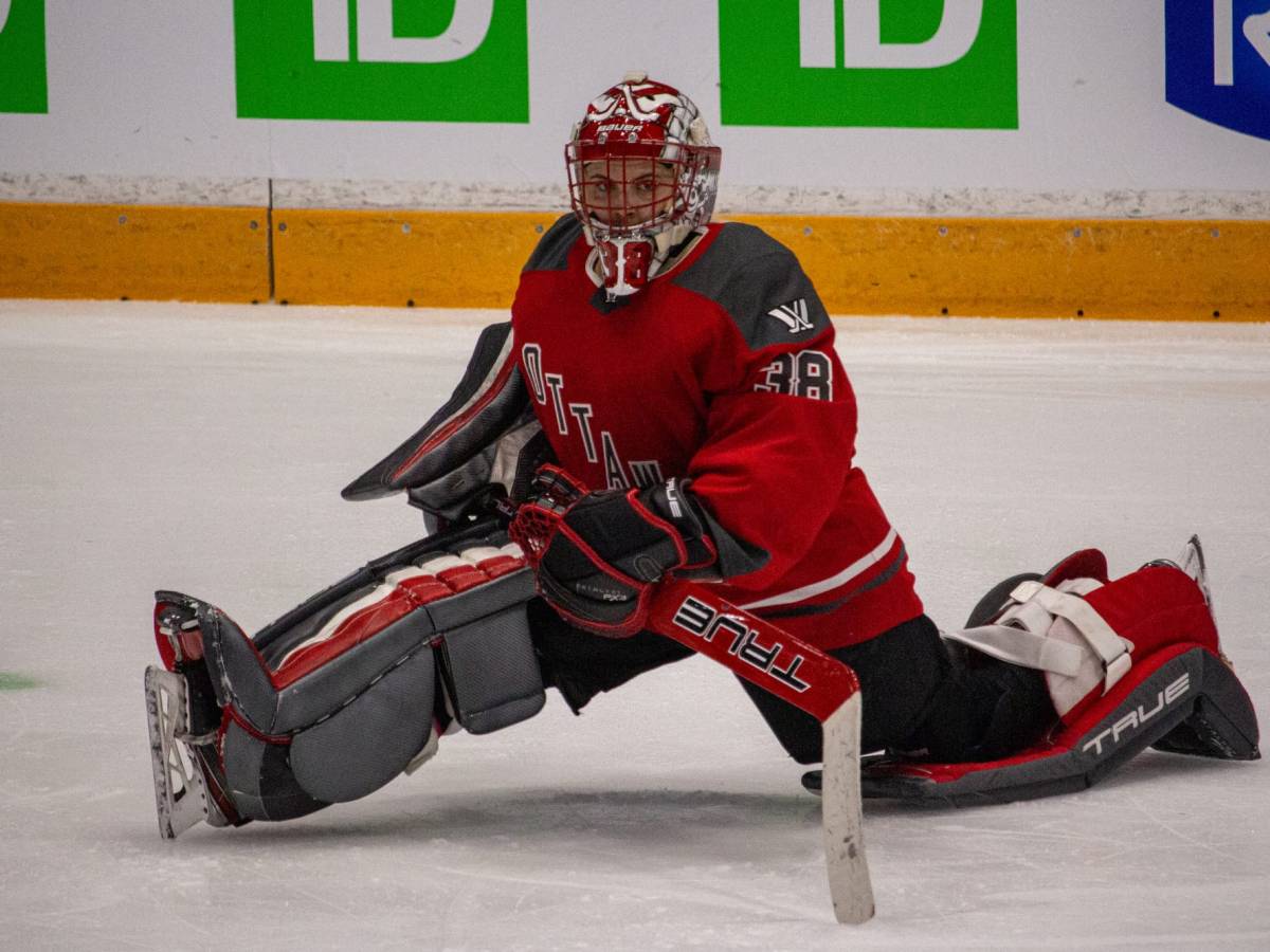 Emerance Maschmeyer stretches on the ice in her goalie equipment.