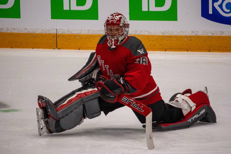 Emerance Maschmeyer stretches on the ice in her goalie equipment.