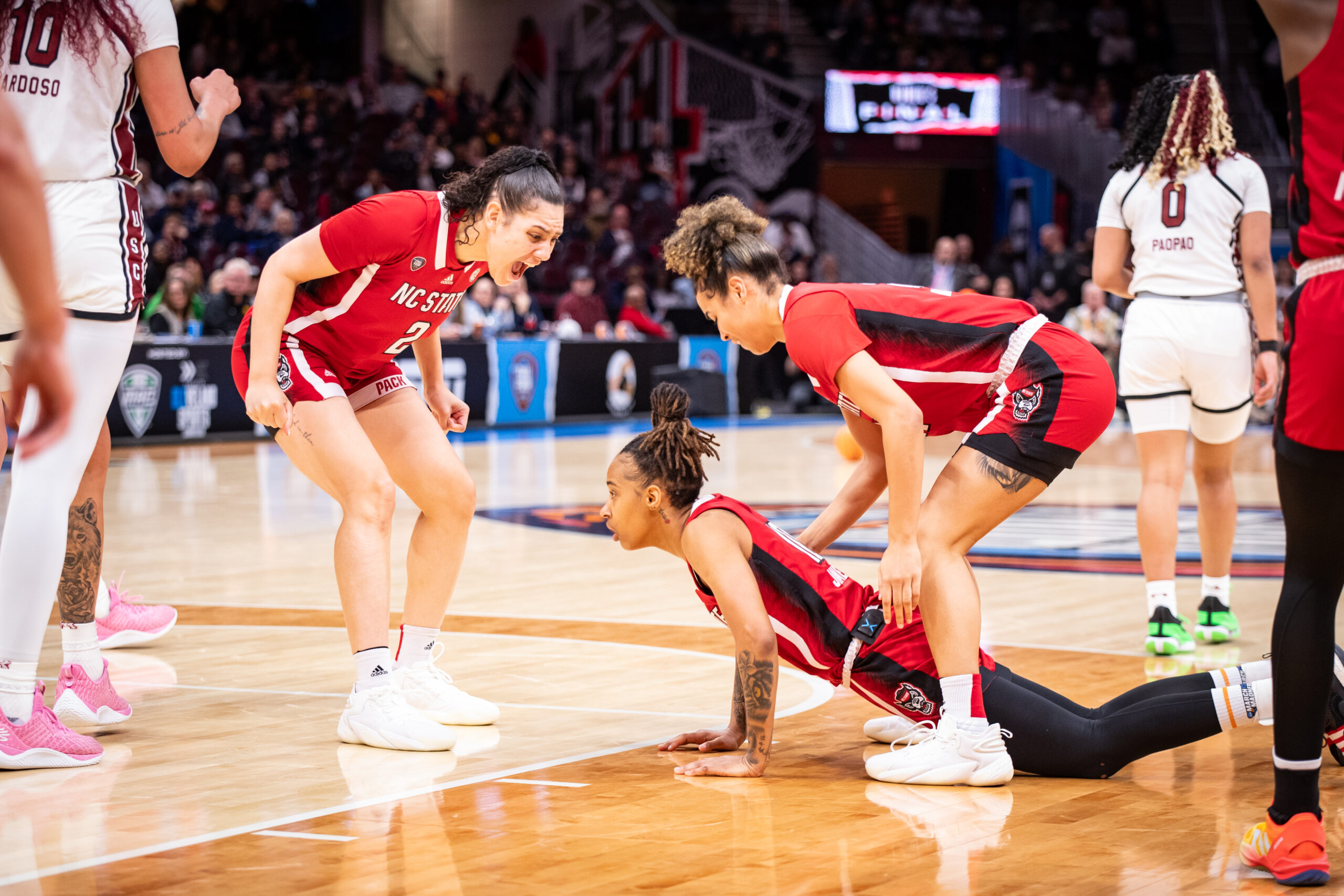 NC State senior Mimi Collins yells in celebration at teammate Aziaha James, who pushes herself up from the court.